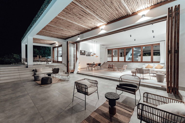 Imagem de referência: varanda gourmet coberta com mesas e iluminação noturna